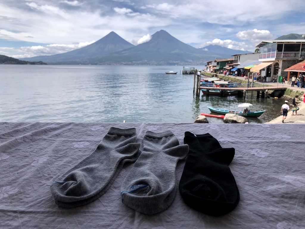 Three pairs of socks on the hostel bed, grey and black, folded the way the market woman left them. The bag they came in is already in the bin.