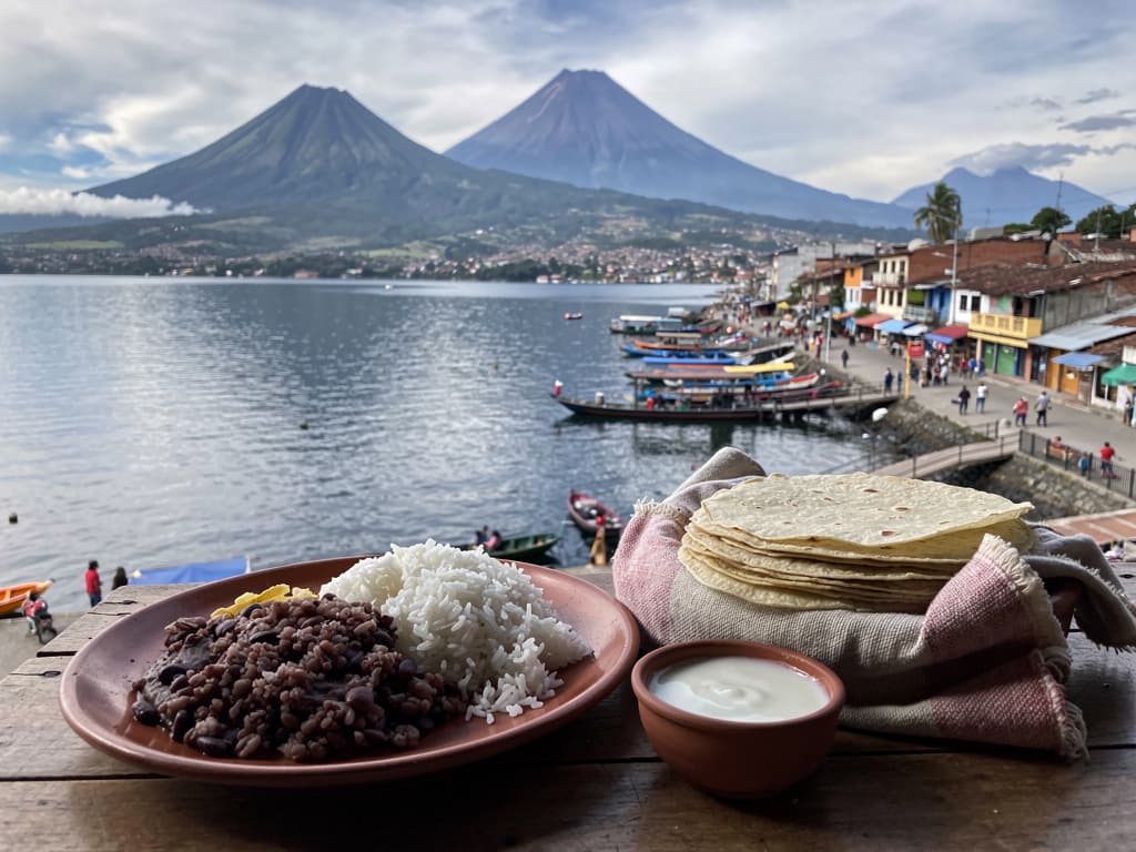 Rice and frijoles in a ceramic plate, small bowl of crema alongside, stack of tortillas wrapped in cloth at a comedor table