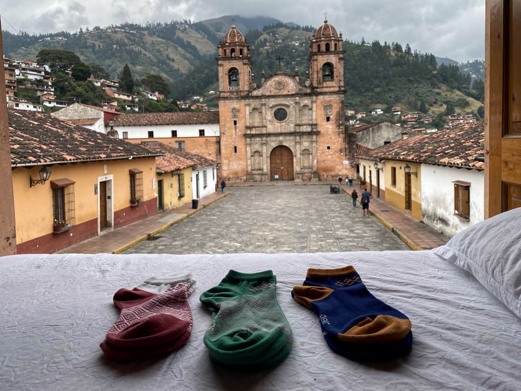 Three pairs of socks on the guesthouse bed, still folded from the mercado stall